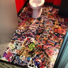 a toilet covered in comics and stickers on the floor next to a wall with red walls