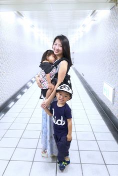 a woman and two children are standing in a hallway with tiled walls on either side