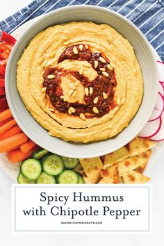 spicy hummus with chipotle pepper in a bowl surrounded by vegetables and crackers