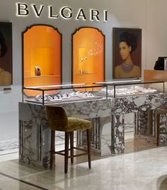 the interior of a jewelry store with paintings on the wall and two stools in front of it