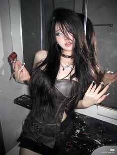 a woman with long black hair holding a rose in her right hand and posing for the camera