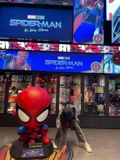 the spider man statue is in front of many movies on display at an indoor mall