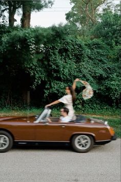 two people riding in the back of a convertible car