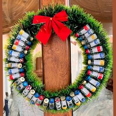 a wreath made out of cans and grass with a red bow on the front door