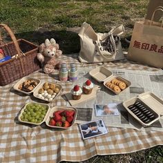 a picnic blanket with food on it and a teddy bear sitting next to the basket