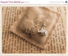 two silver earrings sitting on top of a piece of paper next to an old book