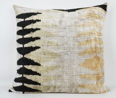 a black and white pillow with an abstract design on the front, sitting against a white wall