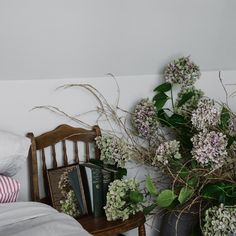 flowers and books on a small table next to a bed