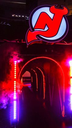 an illuminated tunnel in the middle of a building with neon lights on it's sides