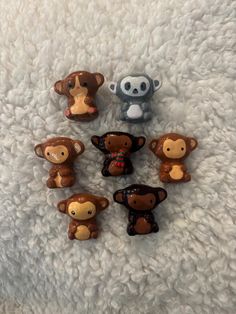 five little monkey figurines sitting on top of a white blanket next to each other