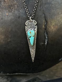 This long arrowhead pendant is gorgeous and perfect for dressing up your look. It is beautifully hand stamped and features a lovely turquoise stone in the middle. This can be purchased as a pendant or as a necklace, please choose which you prefer from the drop down menu. **No two Turquoise stones are the same, and you will not receive the stone pictured. If you have a color preference (more blue, greenish) please let us know in the notes section and we will accommodate you.** This pendant measures 2 3/4" long by 3/4" at it's widest point. Southwestern Arrowhead Jewelry Gift, Southwestern Style Arrowhead Jewelry Gift, Artisan Turquoise Etched Jewelry, Artisan Etched Turquoise Jewelry, Bohemian Stamped Turquoise Necklace, Unique Engraved Turquoise Necklace, Engraved Turquoise Necklace, Southwest Necklace, Arrowhead Pendant