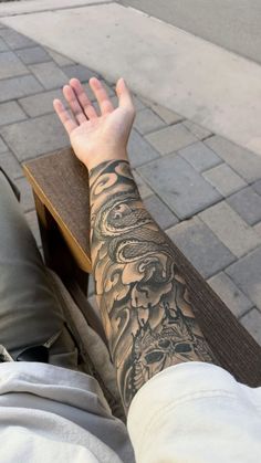 a person with a tattoo on their arm sitting down next to a wooden table and bench