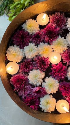 flowers and candles are floating in a bowl