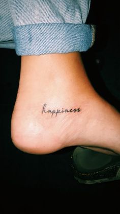 a person with a tattoo that says happiness on their foot