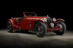 an old red car is parked in the dark