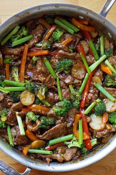 a pot filled with meat and veggies on top of a wooden table