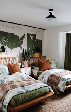 two beds in a room with green curtains and pillows on the bed, next to each other