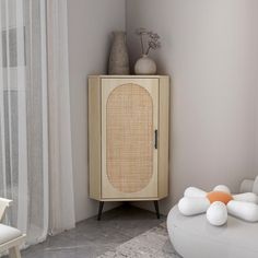 a white and beige cabinet sitting next to a chair in a room with sheer curtains