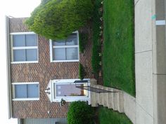 an aerial view of a brick house with grass on the lawn and steps leading up to it