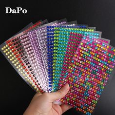 a hand holding five different colors of beaded sheets with the words dapo on them