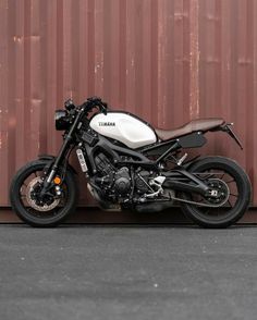 a white and black motorcycle parked next to a wall