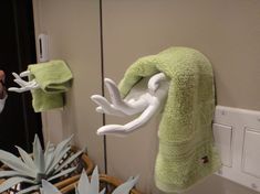 a green towel hanging from a hook on a wall next to a basket with succulents