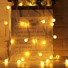 there is a sign with lights on it in front of a brick wall and potted plant