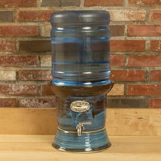 an old fashioned water dispenser sitting on top of a wooden table