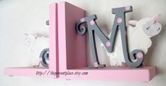 the letters m and m are made out of wood, with sheep on each shelf