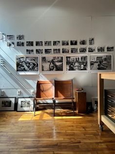 a chair sitting on top of a hard wood floor next to a wall covered in pictures