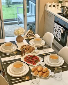 a table set for two with plates and cups filled with tea, bread, and fruit