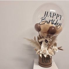 a vase filled with balloons and flowers on top of a table