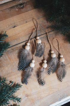 several ornaments are hanging on a wooden table next to pine cones and fir tree branches