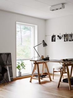 a white room with wooden floors and two desks in front of a large window