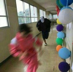 two people walking down a hallway with balloons and lights on the wall in the shape of hearts