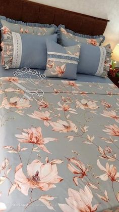 a bed with blue and pink floral comforter set on it's headboard