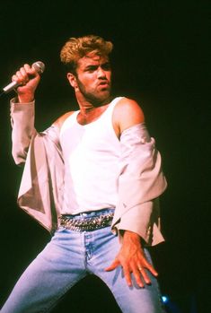 a man in white shirt and jeans holding a microphone