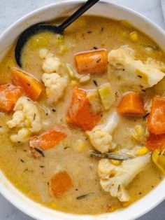 a bowl of soup with carrots, cauliflower and other items in it