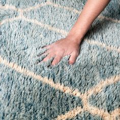 a person's hand on top of a blue rug