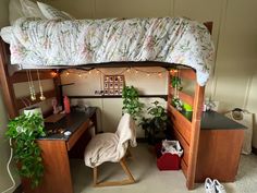 a loft bed with a desk underneath it and some plants on the floor next to it