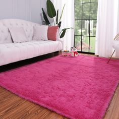 a living room with a pink rug on the floor and a white couch in front of it