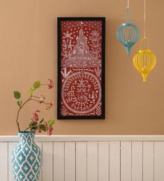 two vases with flowers in them are next to a wall hanging on the wall