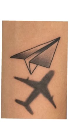 an airplane and plane shadow on the back of a woman's arm, with black ink