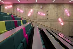 an empty auditorium with rows of seats and neon lights on the wall behind them,