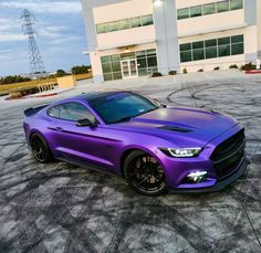 a purple mustang parked in front of a building