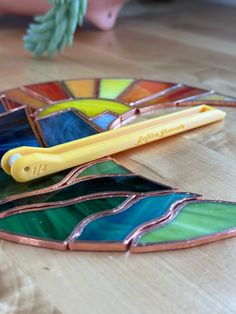 a yellow toothbrush sitting on top of a table next to a stained glass piece