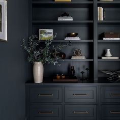 a black bookcase with gold handles and drawers in a living room area that is painted dark blue