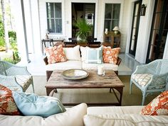 a living room filled with lots of furniture next to a patio area covered in windows