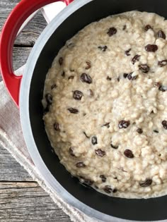 oatmeal with raisins in a red pot on a wooden table