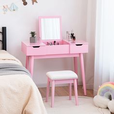 a pink vanity table with a mirror and stool in the corner next to a bed